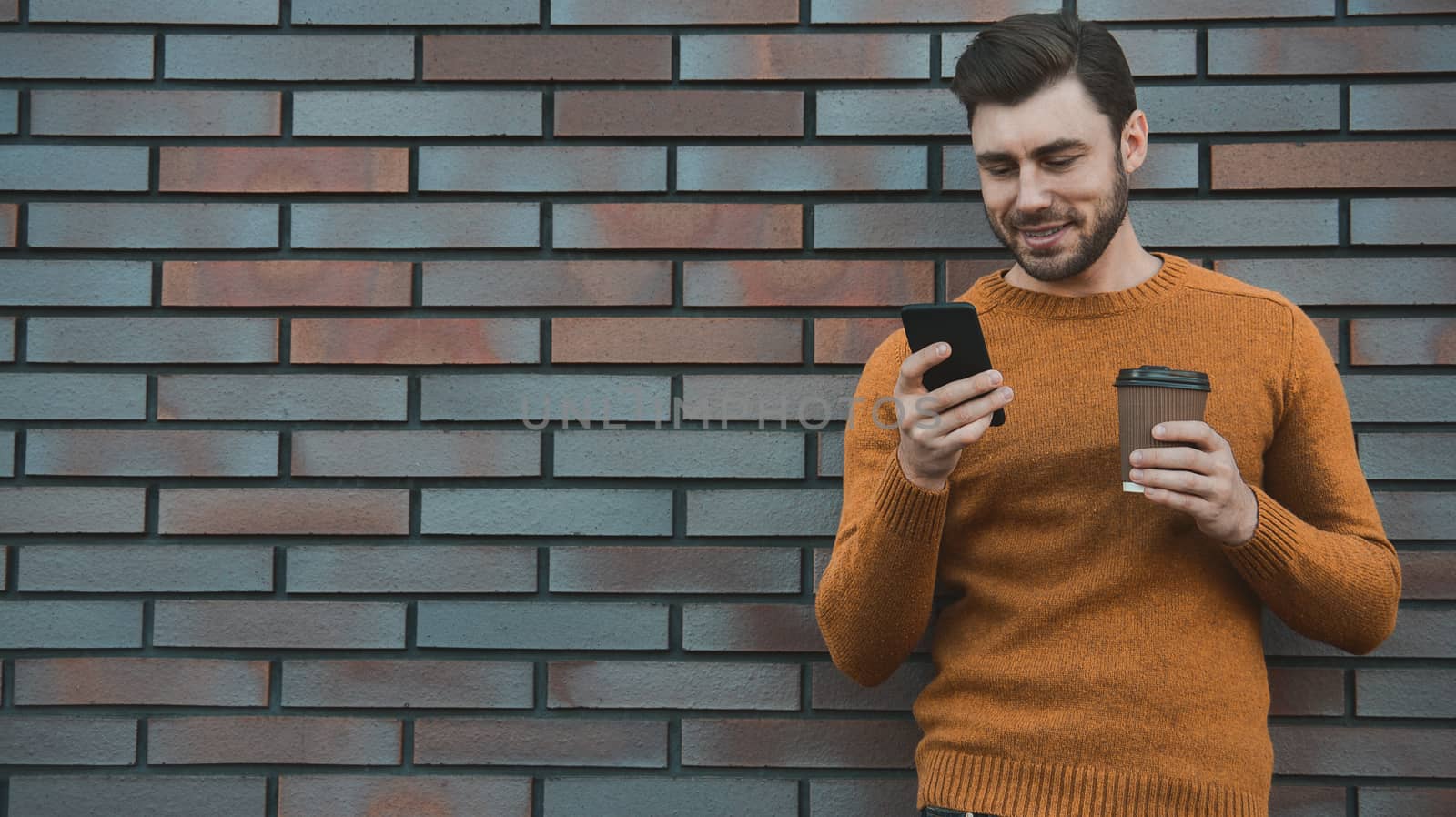 Amazing man holding smartphone in smart casual wear standing.