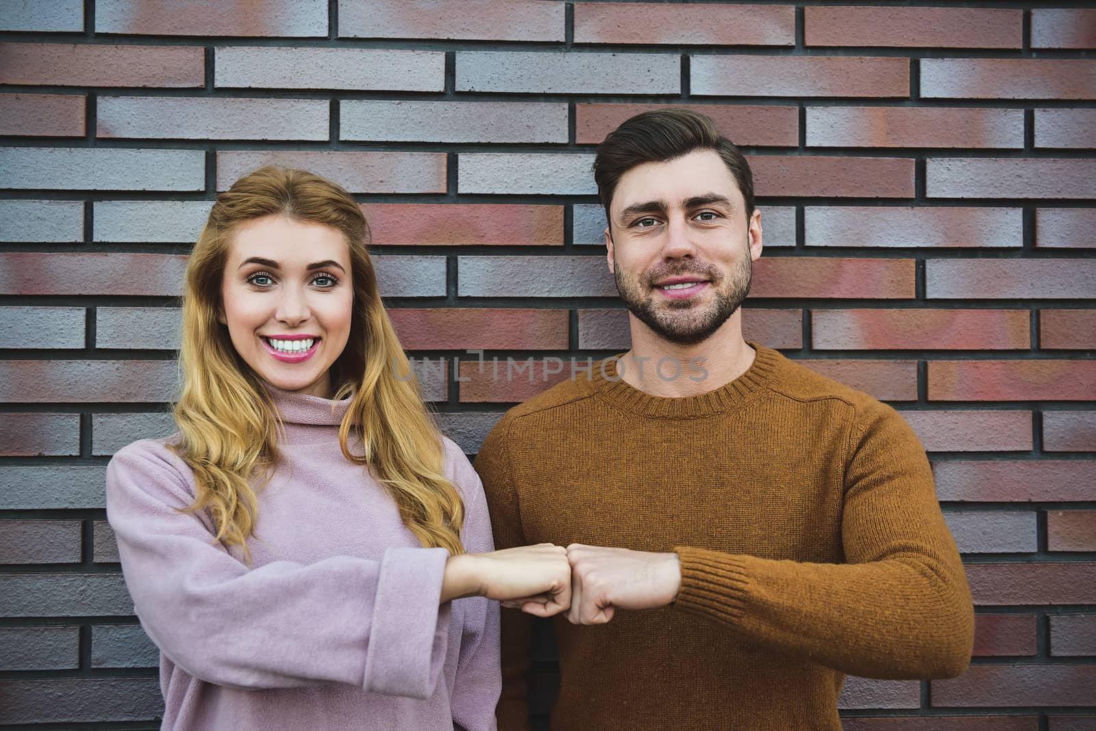 Graceful cheerful positive young woman and man have satisfied expressions, keep both hands on heart, feel thankful to guests, being in high spirit, stand against white background.