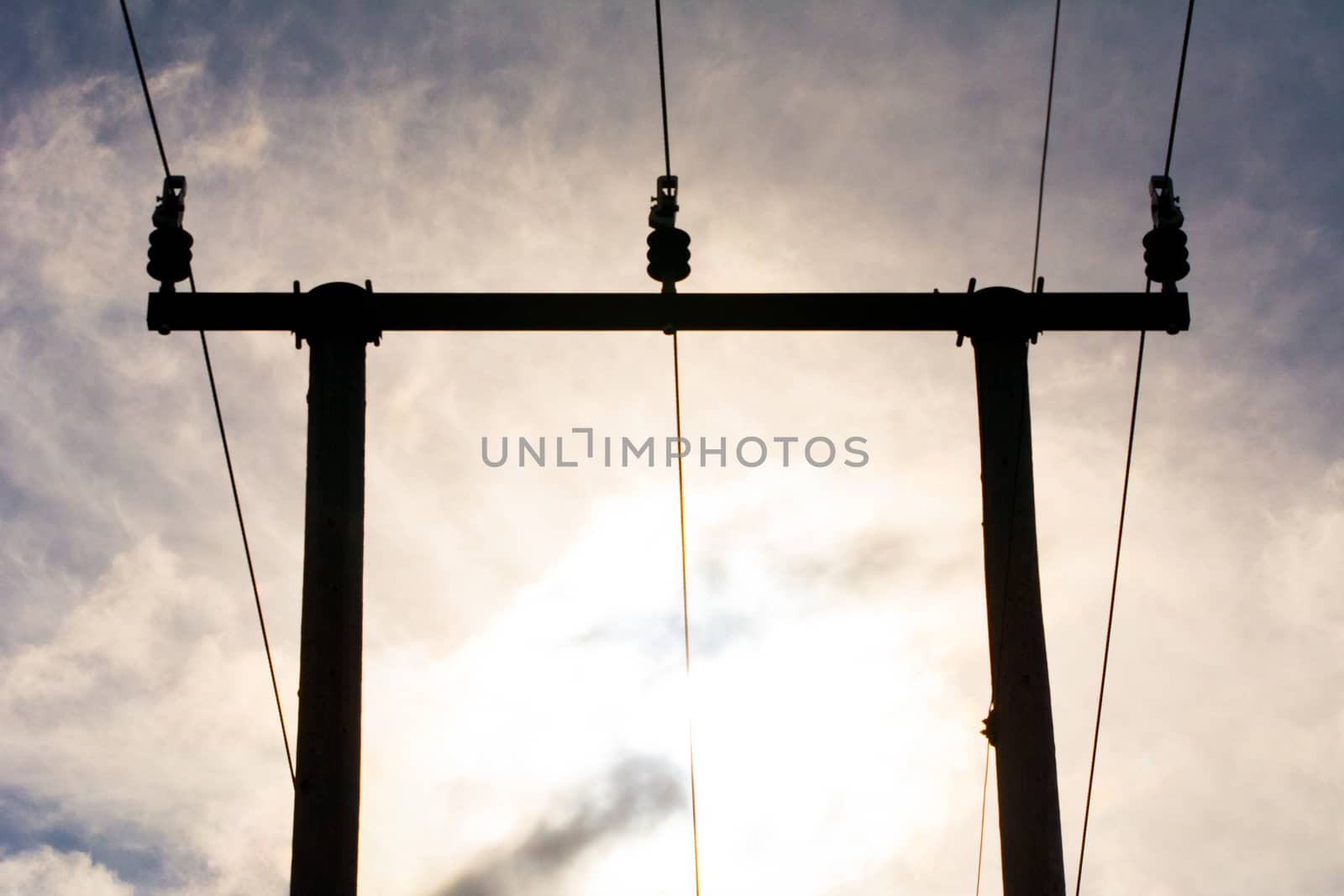 Wooden utility poles in silhouette with electricity wires on a cloudy sky during sunset. by kb79