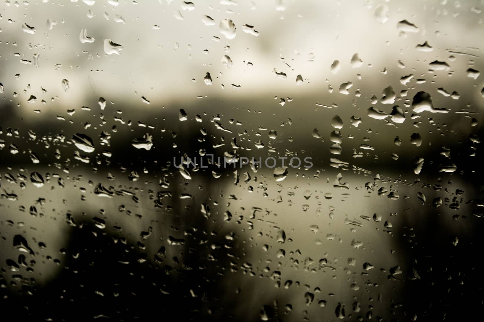 Rain drops on a window with dark background, moody and dark, autumn or winter rain.