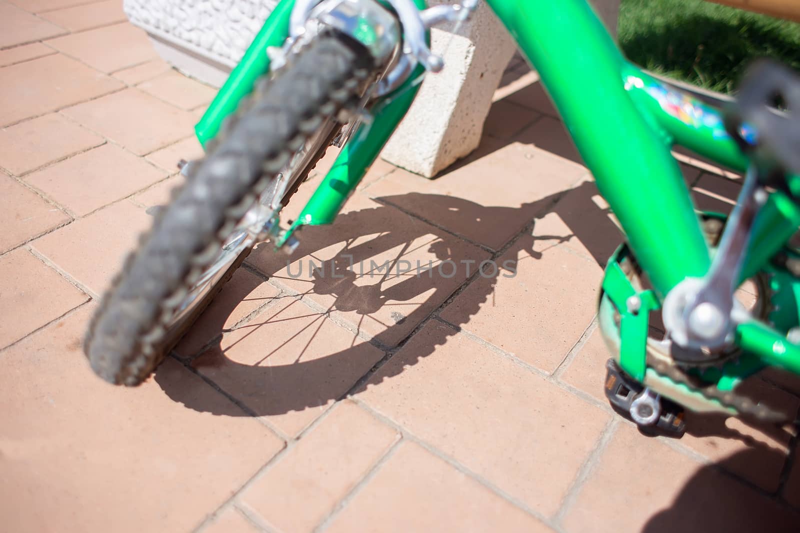 Children's bicycle wheel and its shadow on the paving stones. Carved shadow from the spokes of a bicycle wheel.