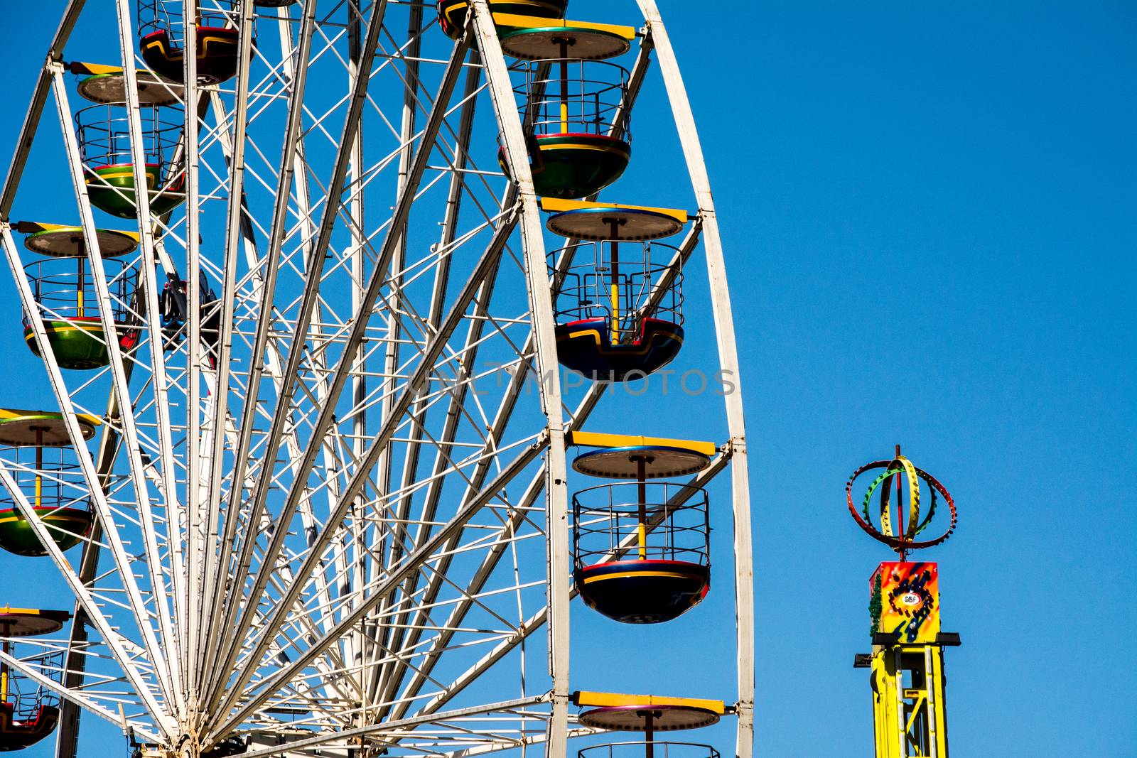 close-up and detail of colorful ferris wheel on blue sky by kb79