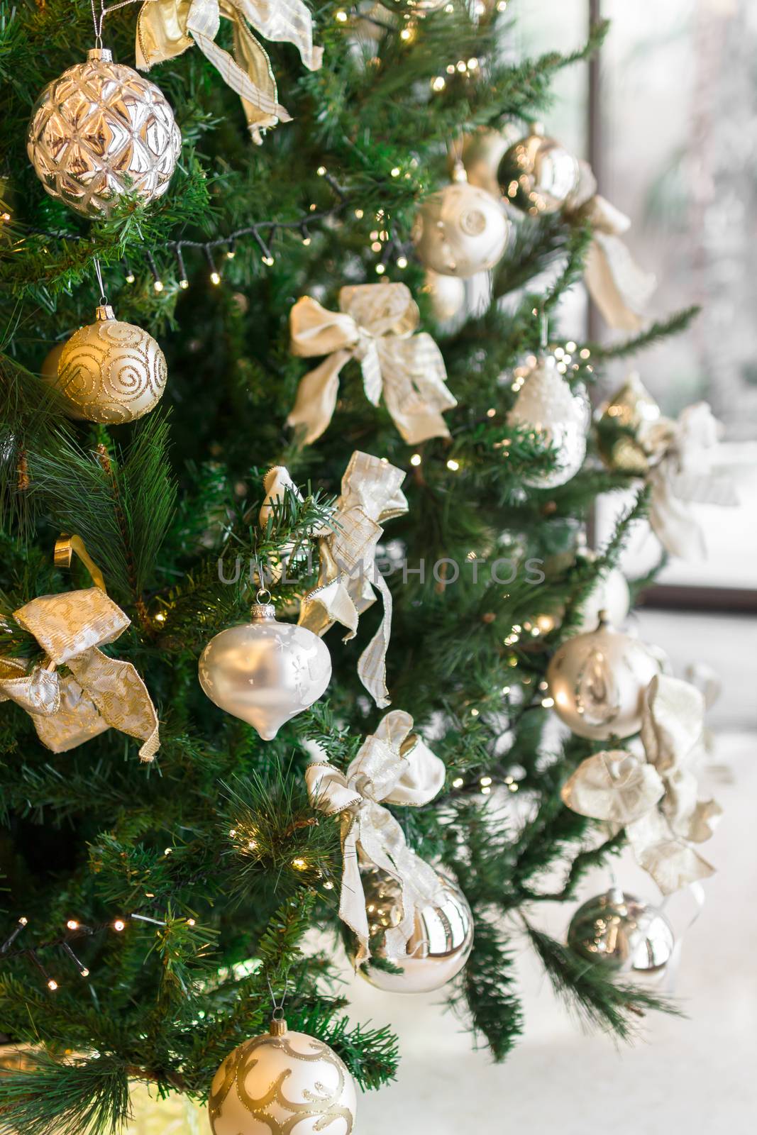 Christmas tree with ornaments, close-up. On background a defocused window. Defocused blurry background.