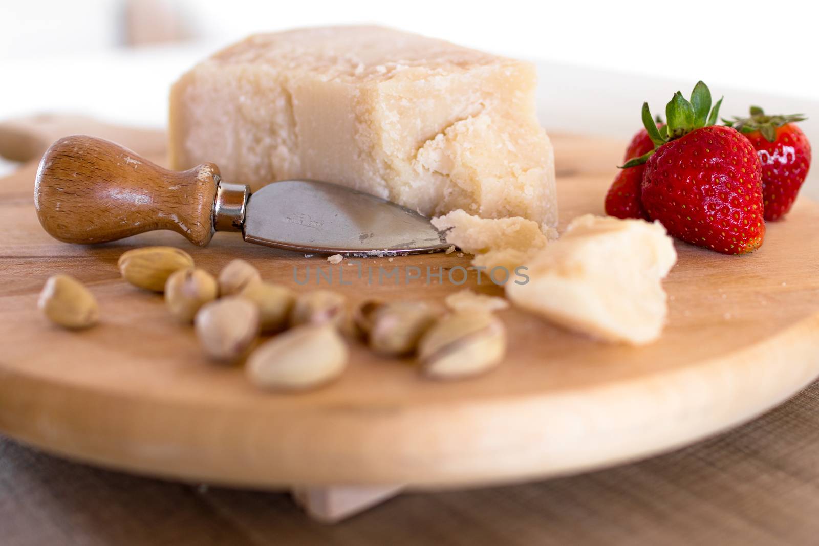 Chopping board with cheese, pistachios and strawberries.