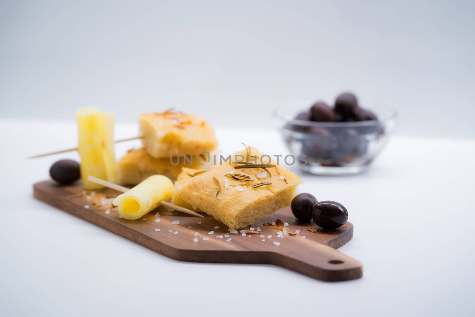 Italian focaccia with rosemary, olives and cheese over a cutting board