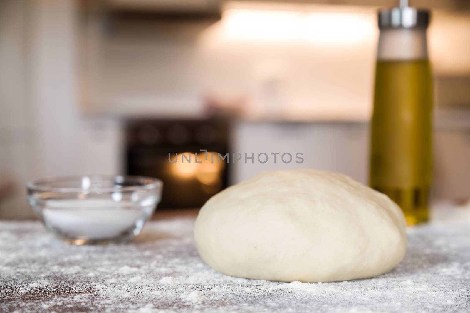 Closeup of dough for pizza over a wooden table in a home kitchen