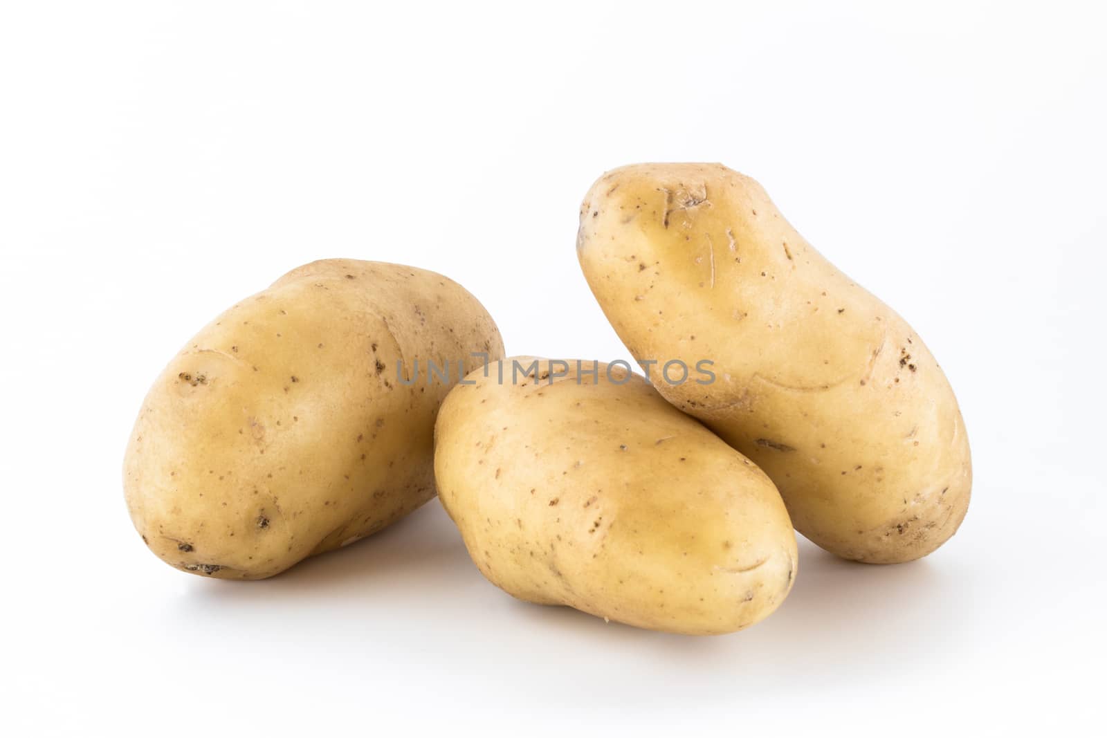 Three raw potatoes, unpeeled, isolated on white background.