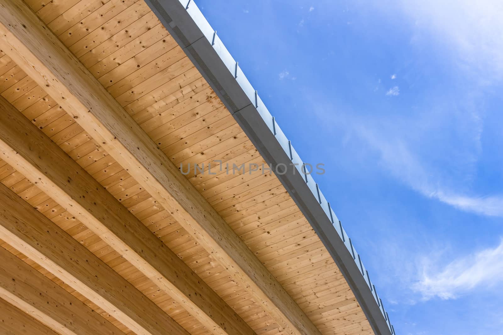Roof of an ecologically clean wooden house against a beautiful cloudy blue sky. Bottom view. Space for text.