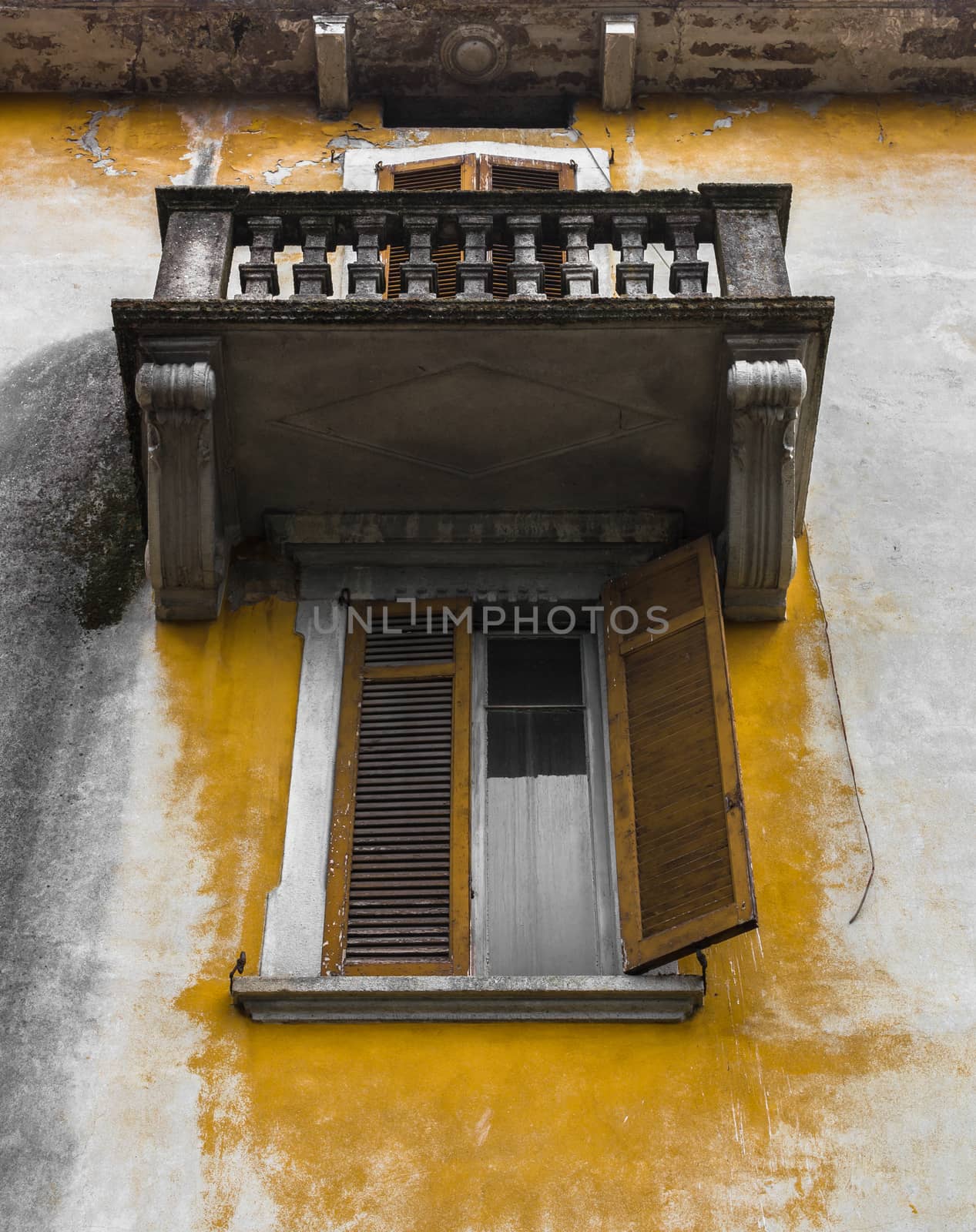 Ancient Italian facade with peeling plaster, near the window and balcony.