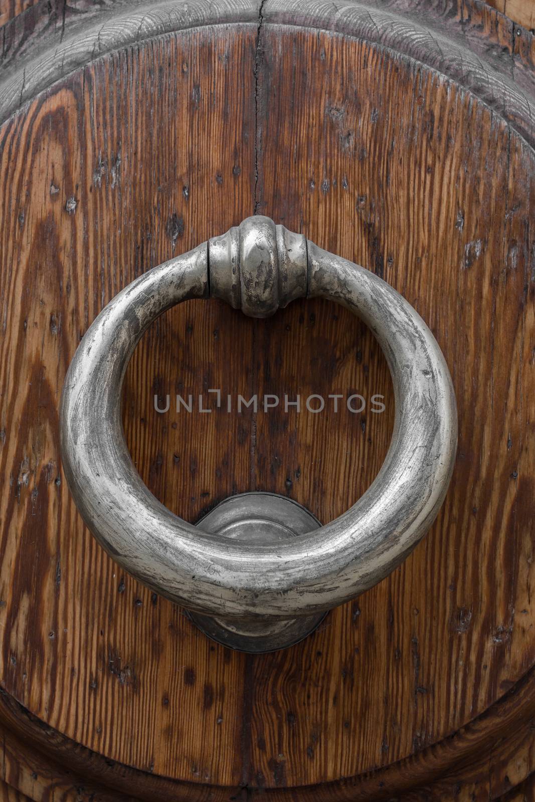 Old brass knocker on wooden door.