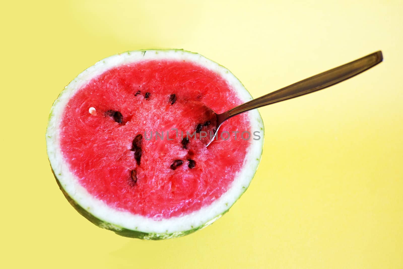 half watermelon with a spoon on a yellow background, copy space. by Annado