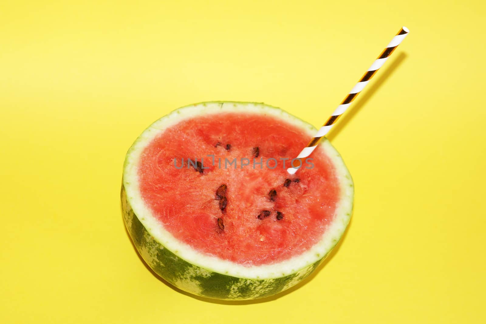 half watermelon with cocktail straw on yellow background, copy space by Annado