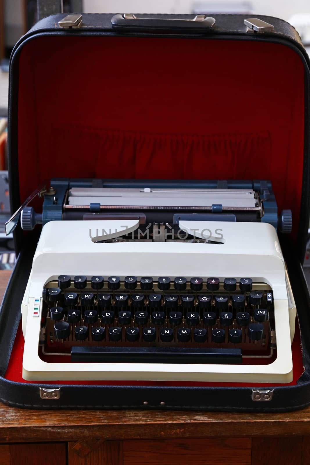 Close up one old portable desk typewriter with Latin alphabet keyboard in open leather case on table, high angle view