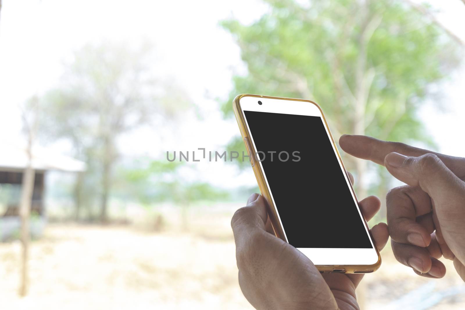 Closeup of a man's hand, a businessman holding a smartphone, and are touch a clean phone screen and a black screen with a mockup design, stay outdoors to play social media, internet, or check stock, along with the vivid visual style on the street background.