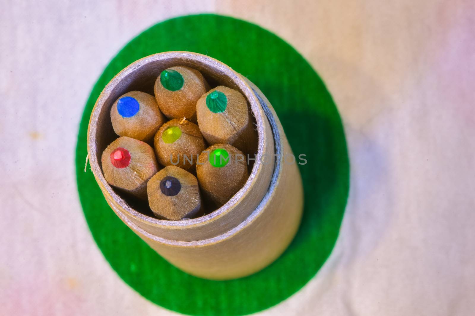 Colored pencils inserted in a cardboard cylinder on a colored plane, horizontal image