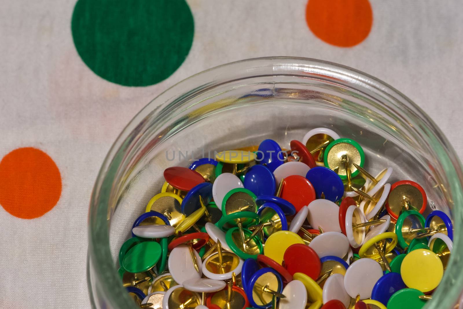 colored thumbtacks in a glass jar by brambillasimone