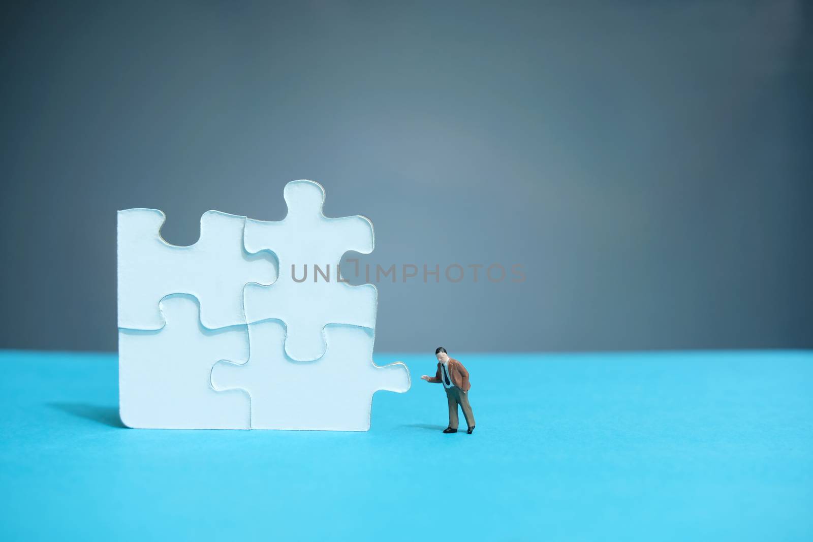 Business strategy conceptual photo - miniature businessman pointing on 4 missing piece puzzle