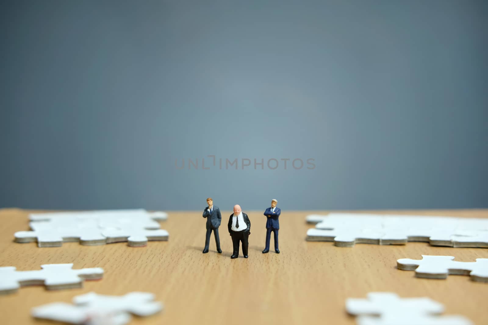 Conceptual photos of business strategies - miniature people businessmen standing in front of uncomplete jigsaw puzzles