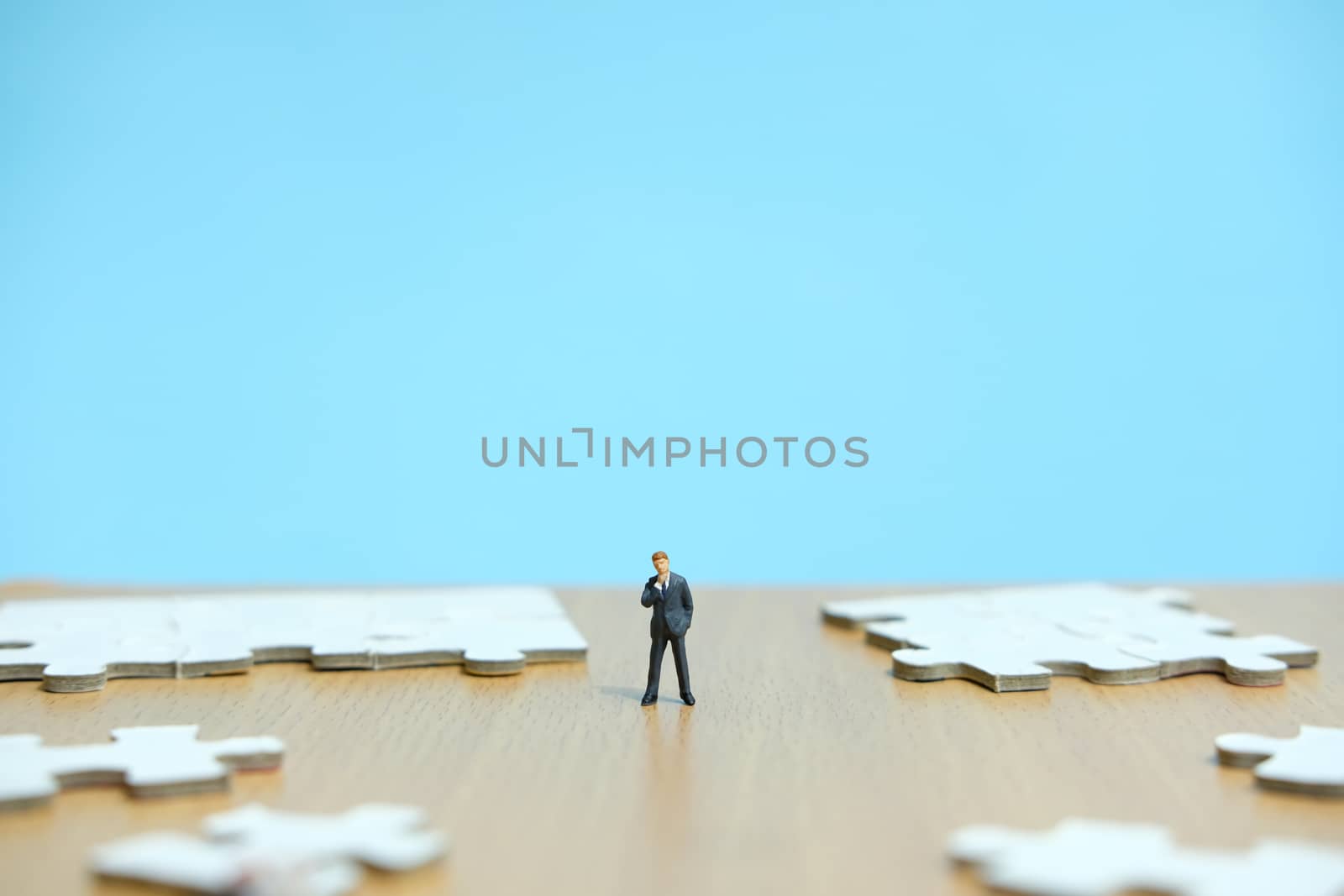 Conceptual photos of business strategies - miniature people businessmen standing in front of uncomplete jigsaw puzzles