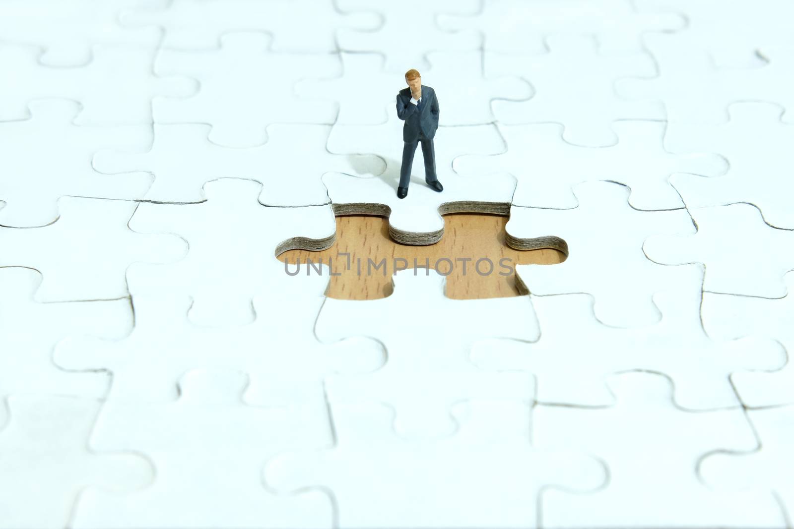 Business strategy conceptual photo - Miniature businessman thinking in front of missing piece puzzle