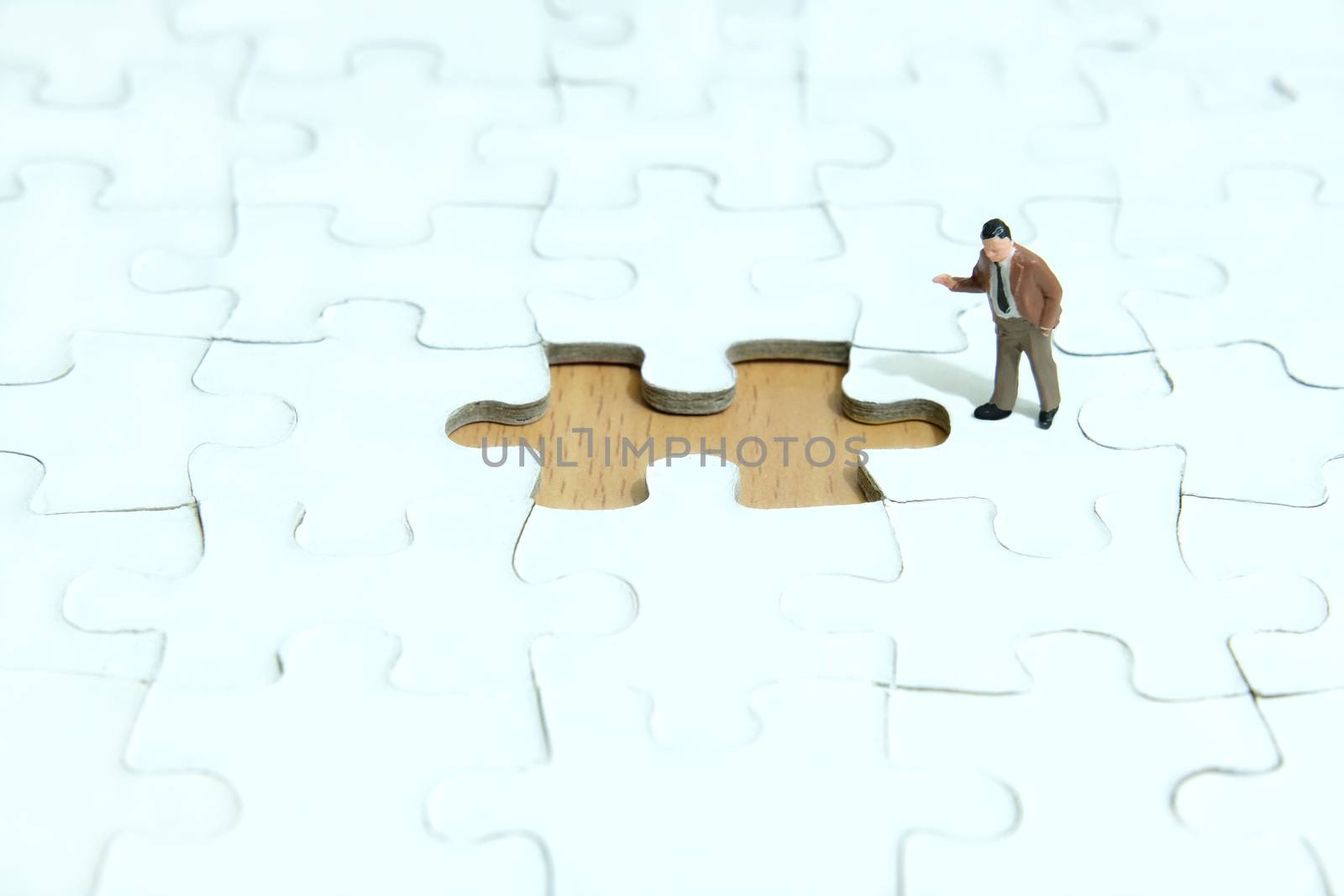 Business strategy conceptual photo - Miniature businessman pointing at missing piece puzzle