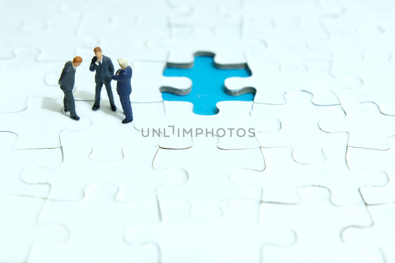 Business strategy conceptual photo - three miniature businessman discussion above missing puzzle jigsaw