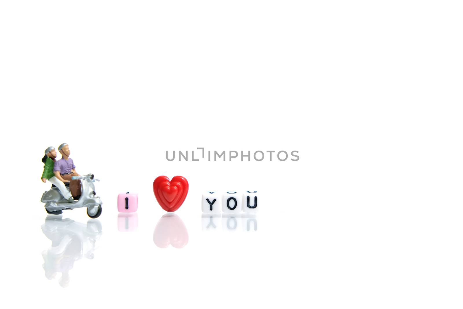 Miniature people photography for valentines day, young couple riding scooter with I love you beads on shiny white background by Macrostud