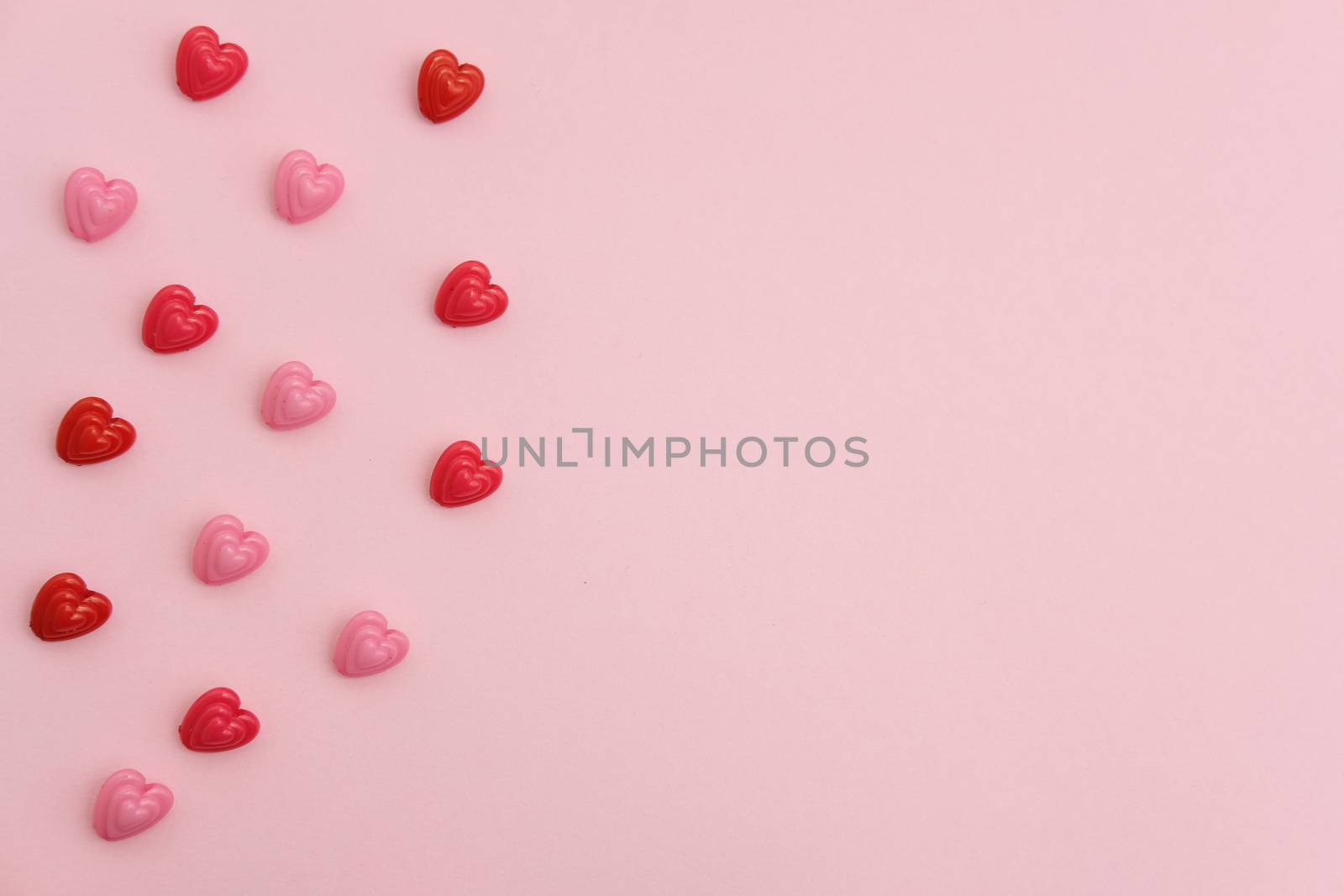 Red and pink heart beads shape, top view flat lay with pink background. Love and romance conceptual object