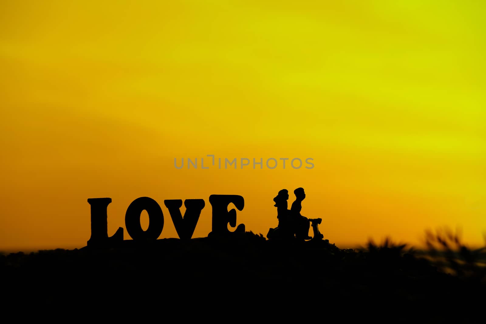 miniature people / toy photography - conceptual valentine holiday illustration. A couple silhouette riding a scooter at the sand beach with love word block