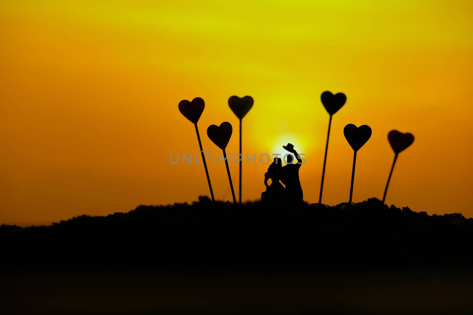 miniature people / toy photography - conceptual valentine holiday illustration. A Couple silhouette walking at the sand beach with heart balloon