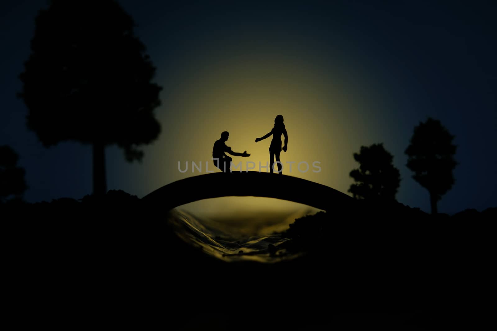 miniature people / toy photography - conceptual valentine holiday illustration. A man proposing a girl silhouette at the bridge under the moon light