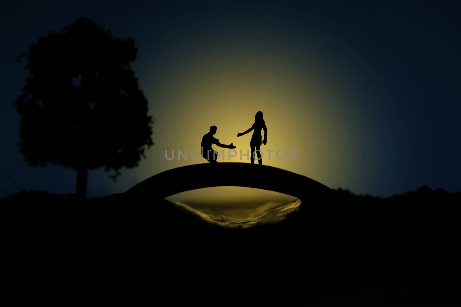 miniature people / toy photography - conceptual valentine holiday illustration. A man proposing a girl silhouette at the bridge under the moon light