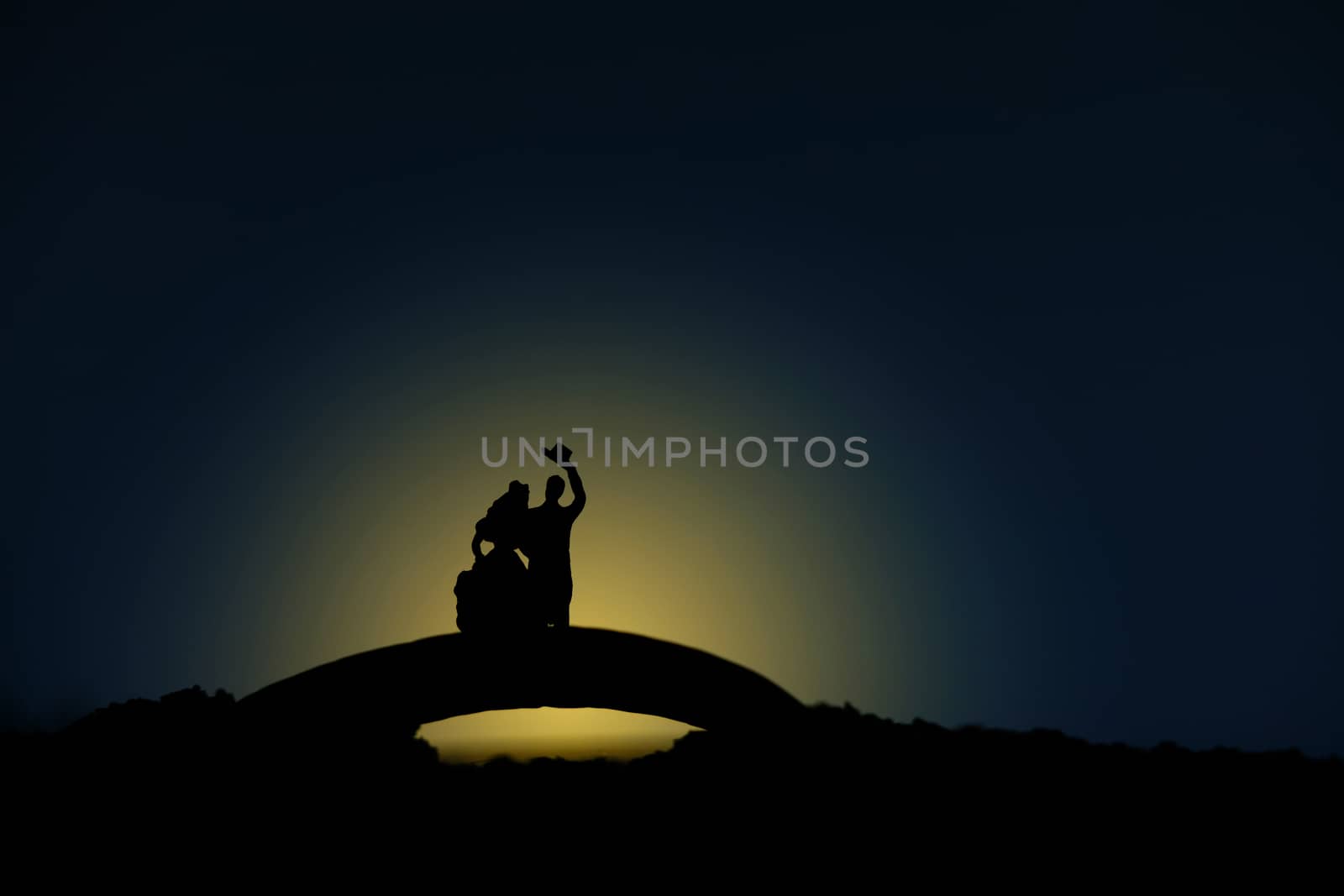 miniature people / toy photography - conceptual valentine holiday illustration. A bride and groom silhouette standing above bridge at night with moon light