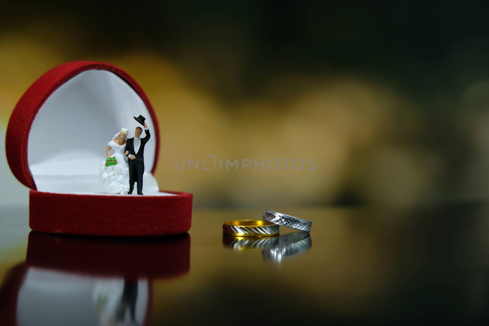 Miniature wedding concept. Bride and groom walking out make greeting above their wedding ring box. image photo
