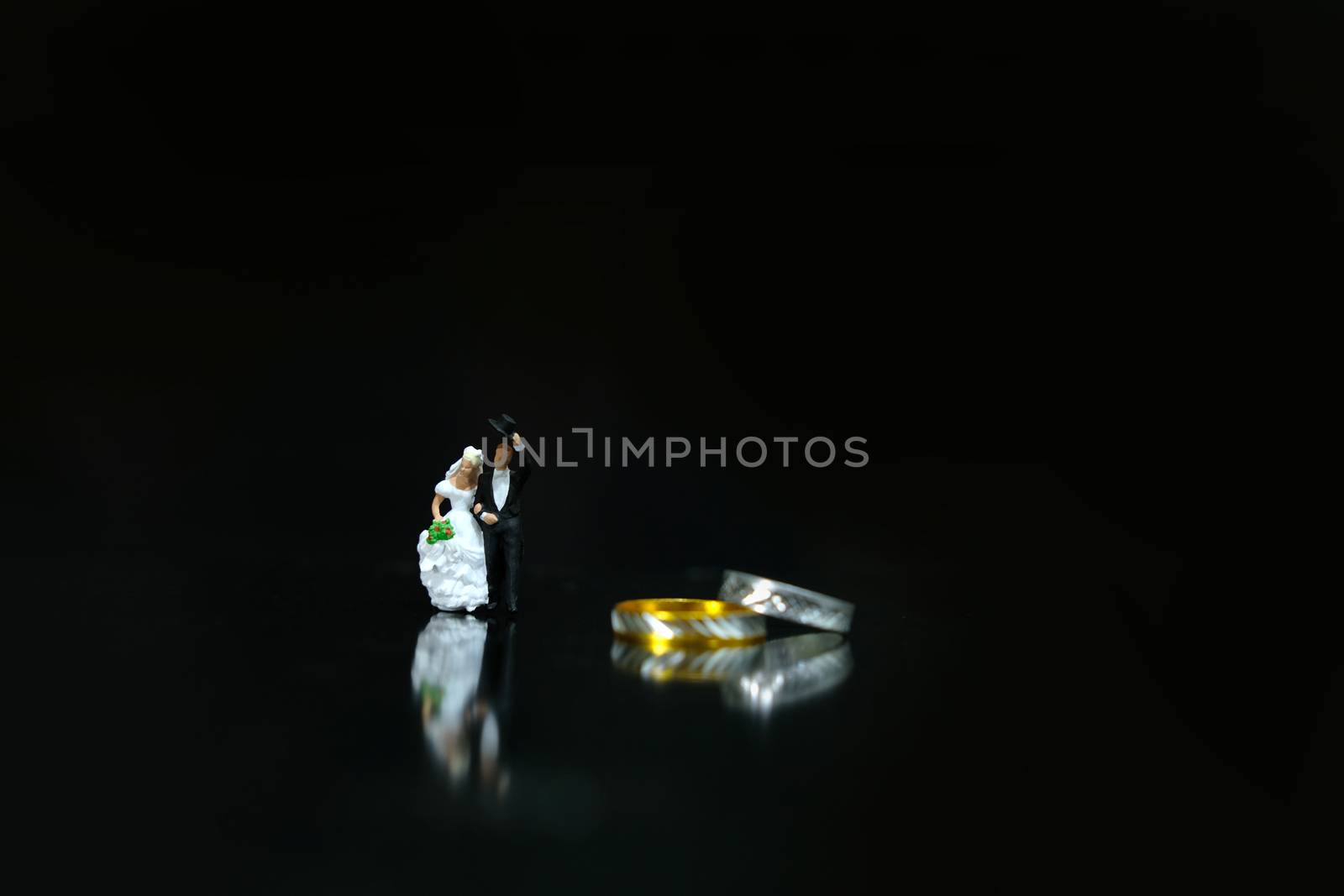 Miniature wedding concept. Bride and groom walking beside their wedding ring. image photo