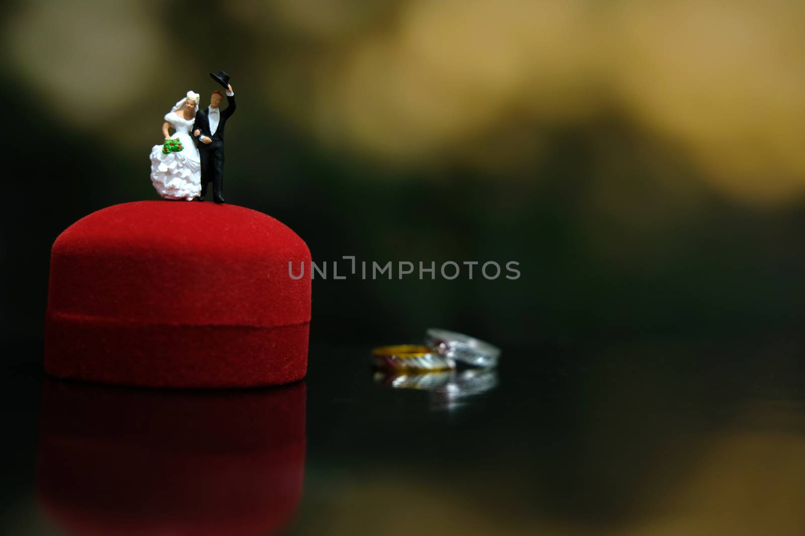 Miniature wedding concept. Bride and groom walking out make greeting above their wedding ring box. image photo