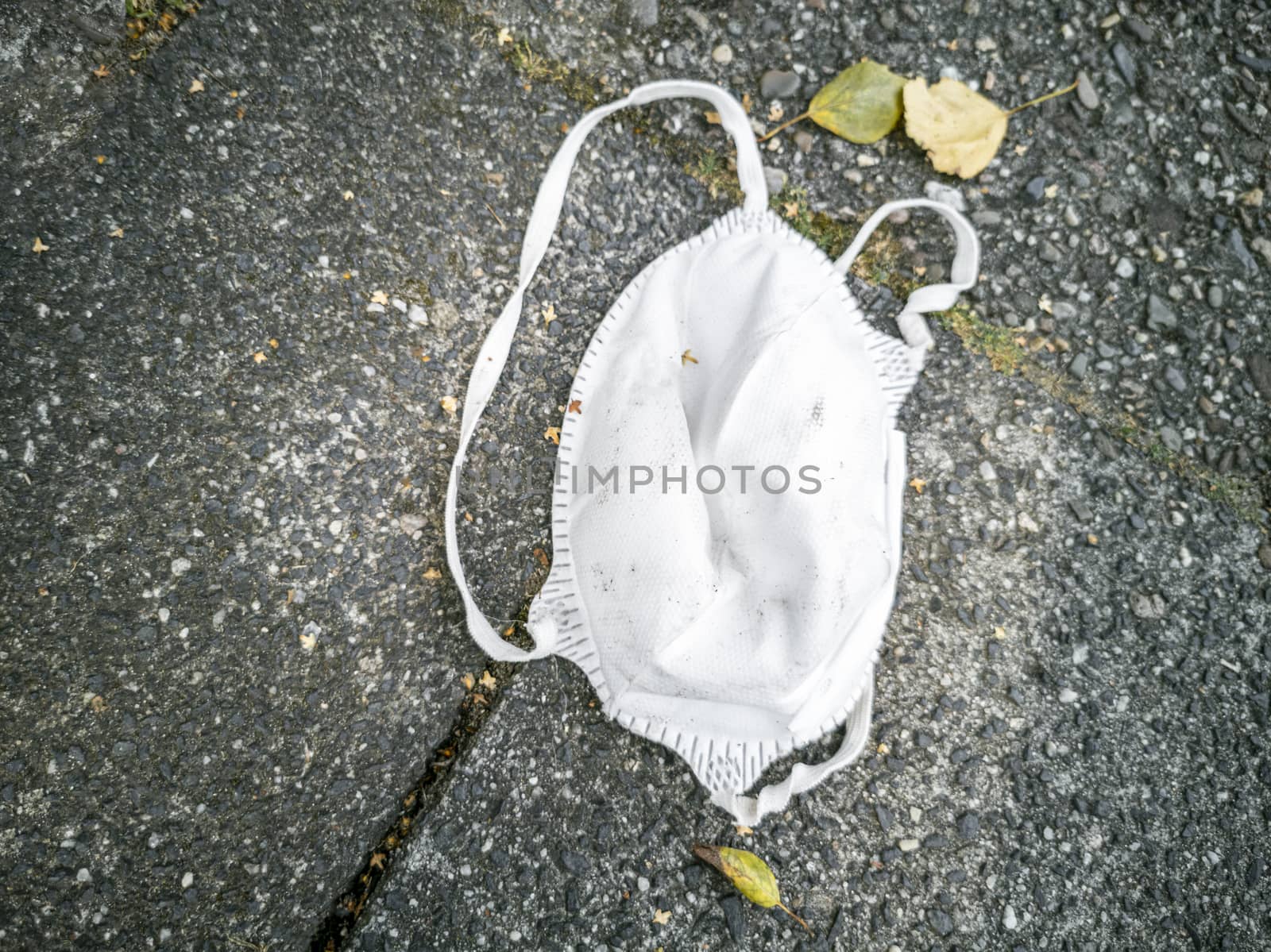 N95 white masks on the ground. Corona virus pollution. by Arkadij