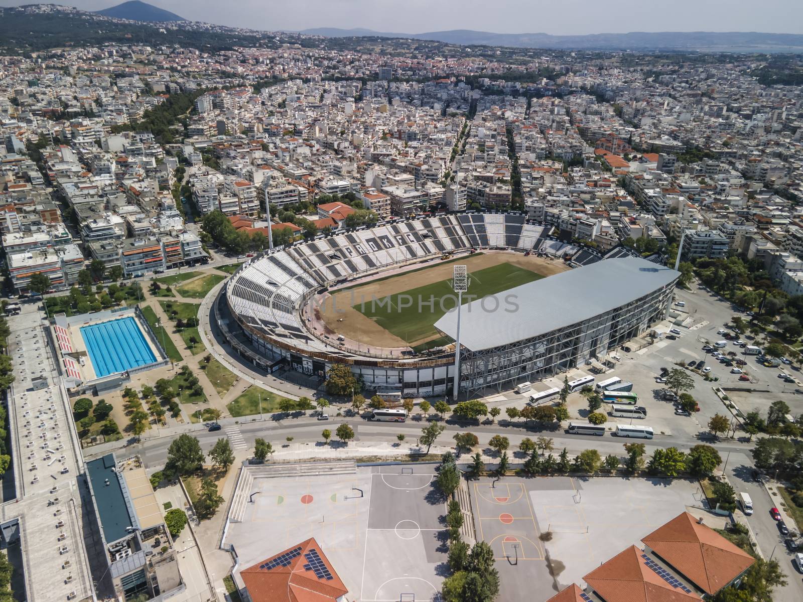 Aerial top day view of empty football court with green pitch and team name written on the stands.