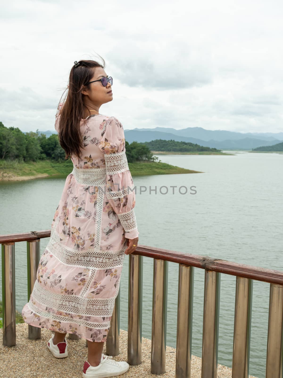 Asian woman Stand on the reservoir background at tourist places in thailand.