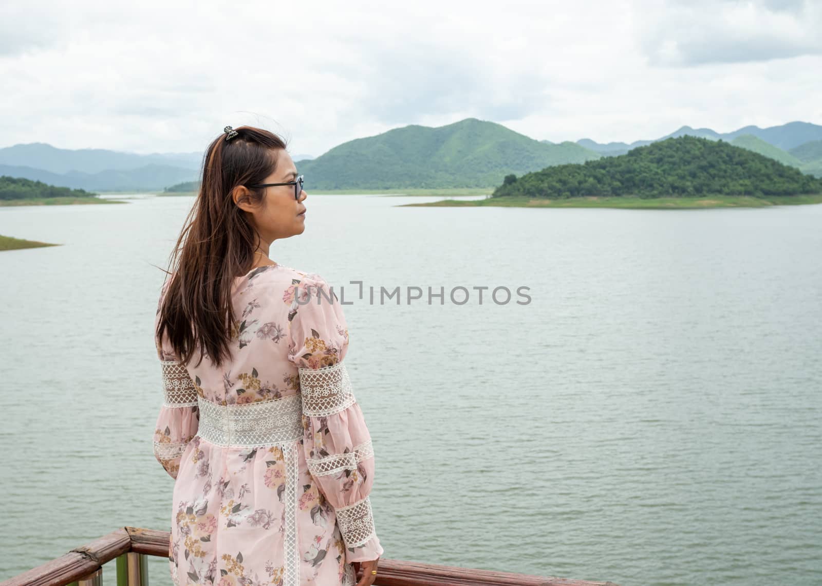 Asian woman Stand on the reservoir background at tourist places in thailand.