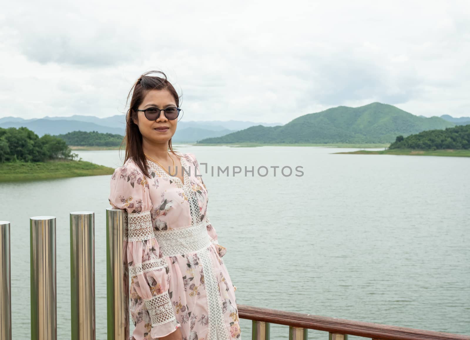 Asian woman Stand on the reservoir background at tourist places by Unimages2527
