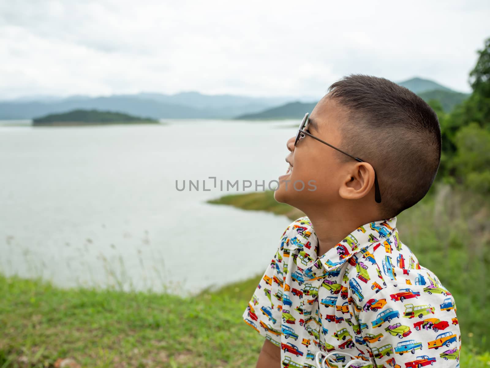 An Asian boy sitting and wearing glasses On the background of th by Unimages2527