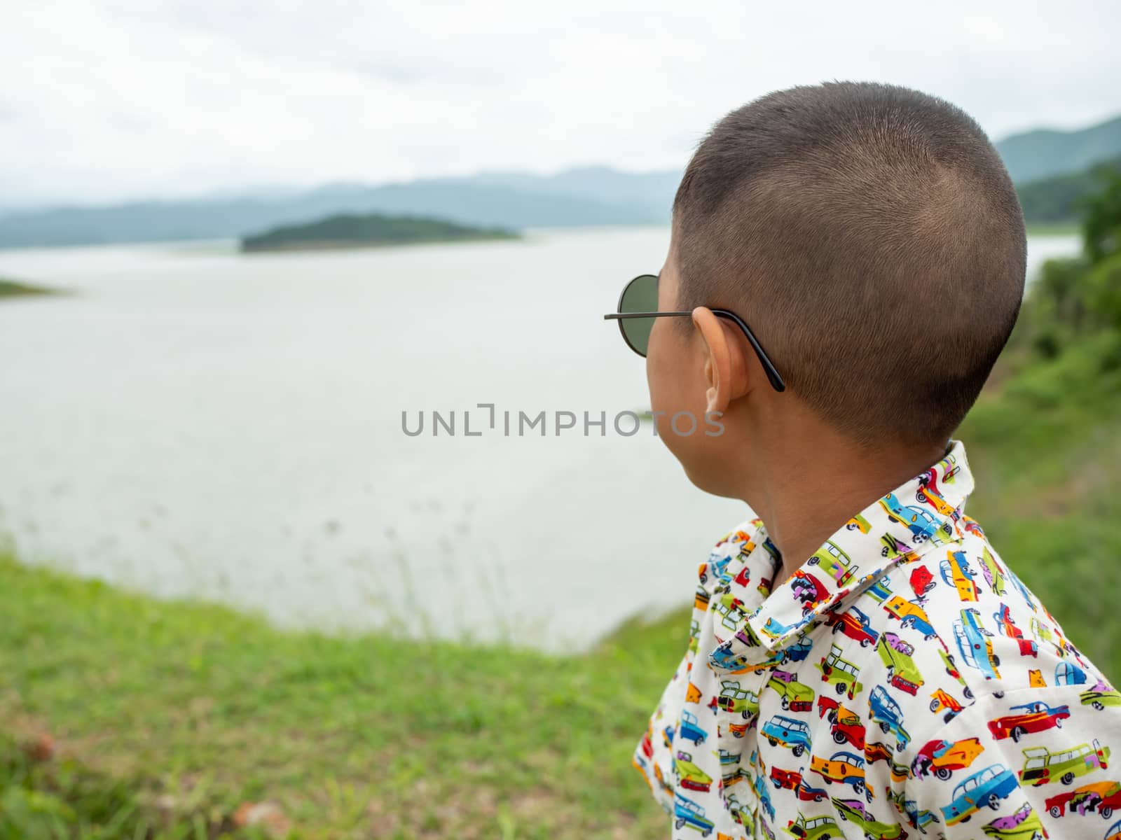 An Asian boy sitting and wearing glasses On the background of th by Unimages2527