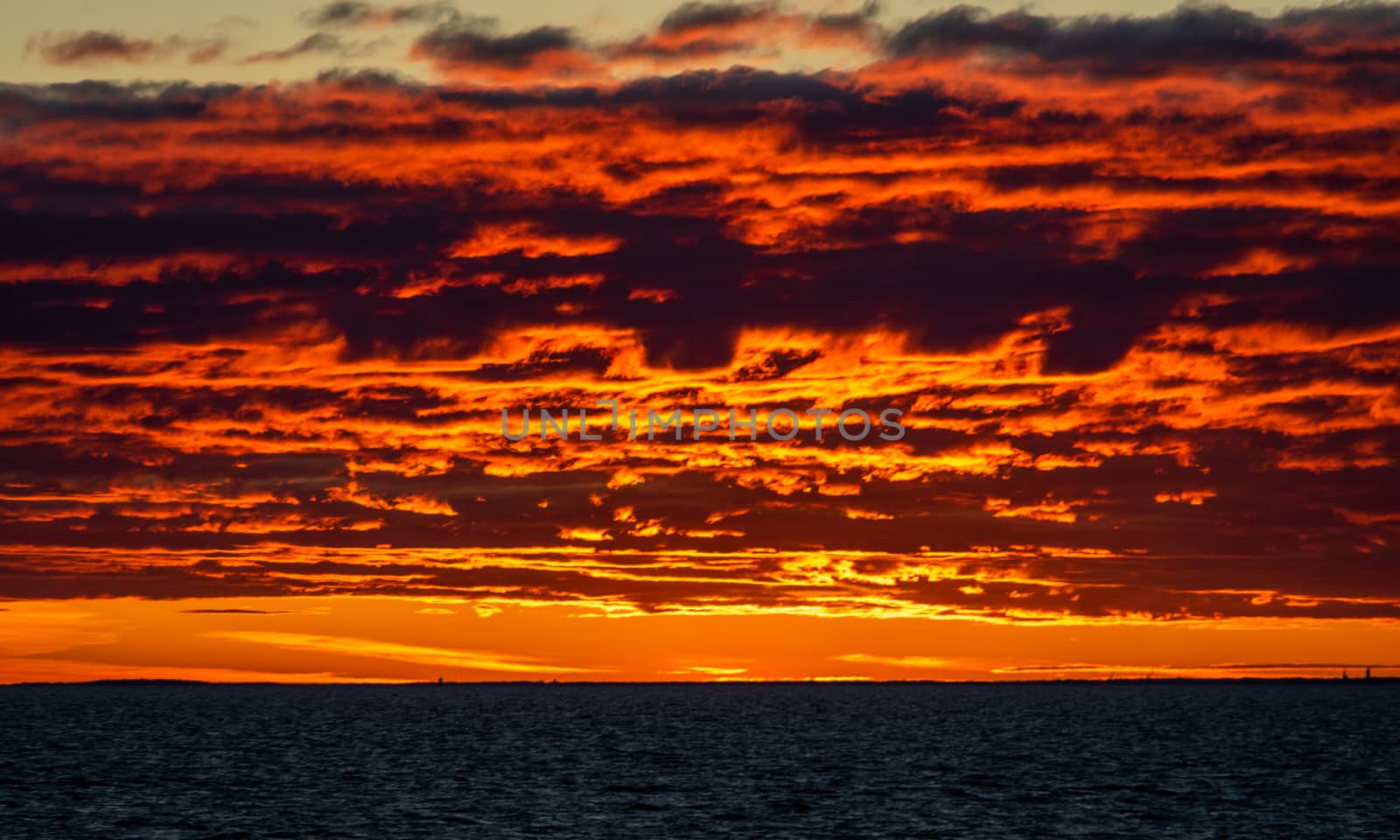 Clouds illuminated by the setting sun over the blue waters of the Baltic Sea.