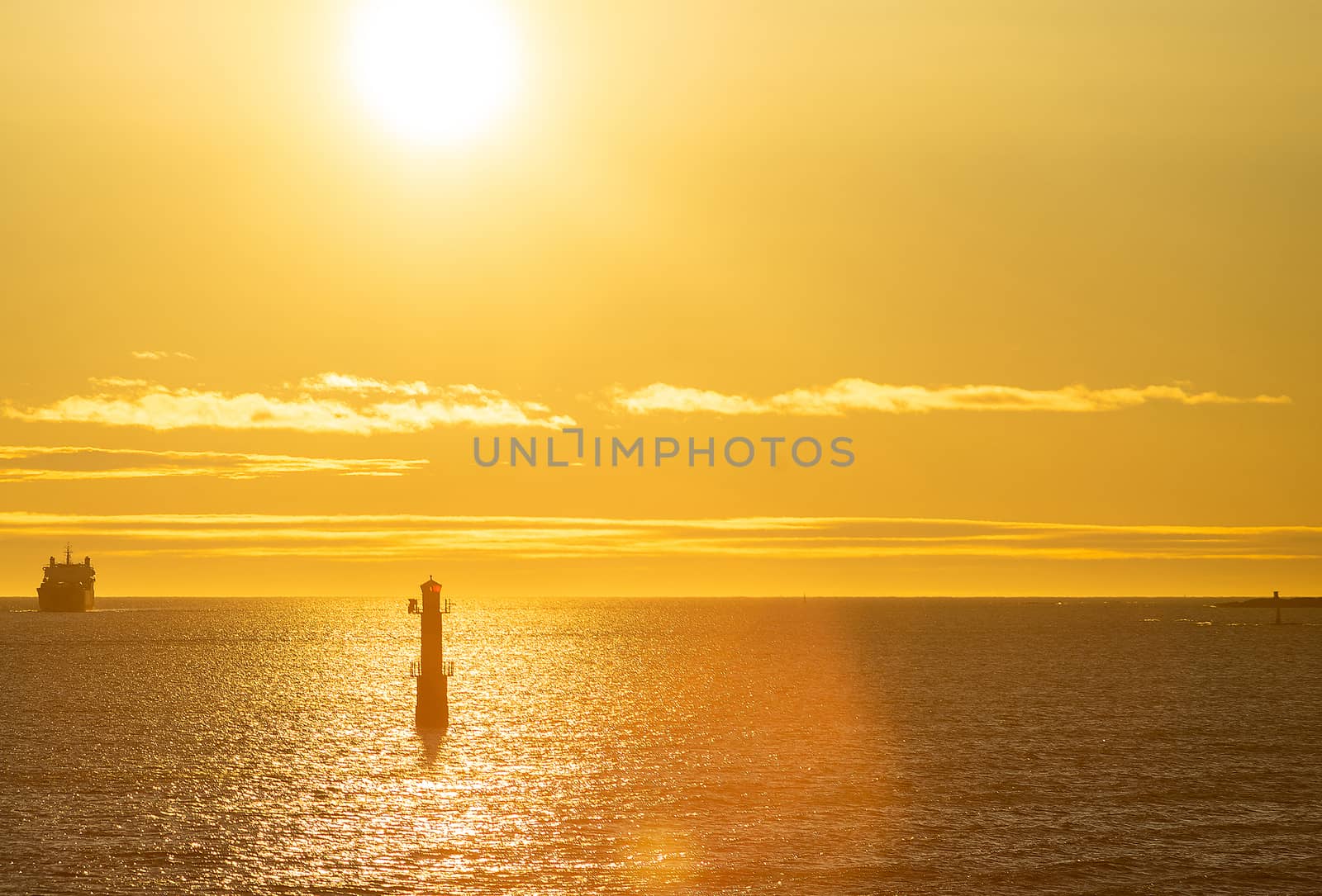 Lighthouse in the strait between the islands of the Stockholm archipelago, lit by the rays of the sun, in the early morning.