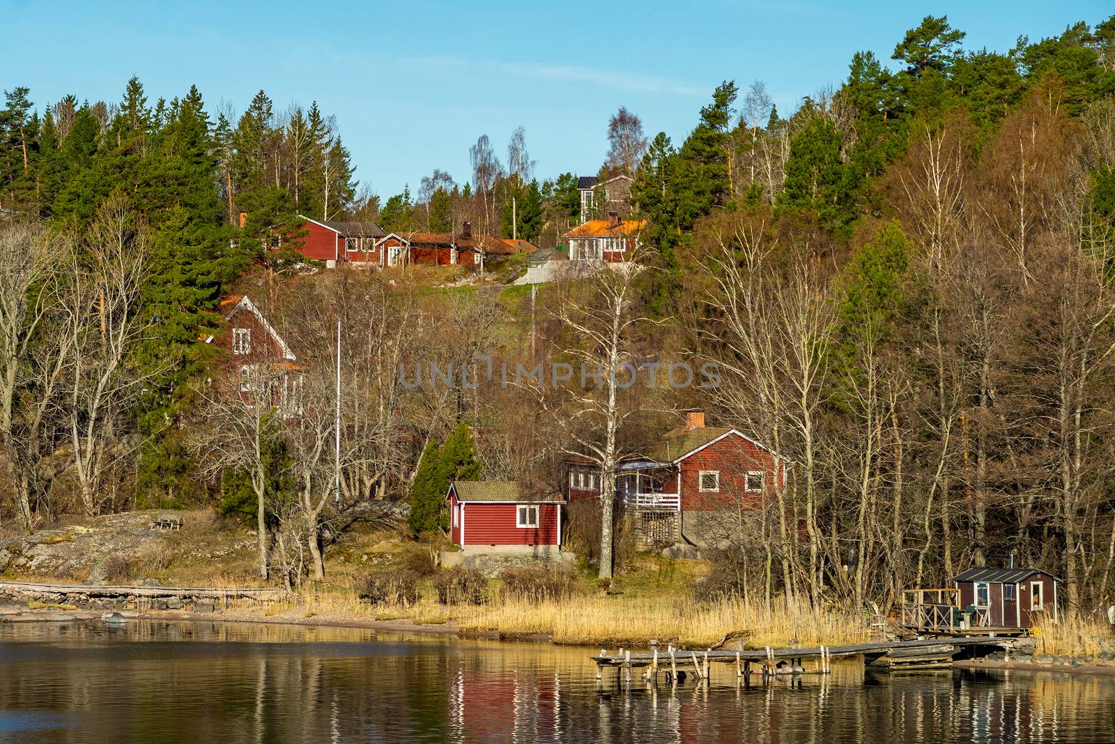 Picturesque summer houses painted in traditional falun red on dwellings island of the Stockholm archipelago in the Baltic Sea in the early morning.