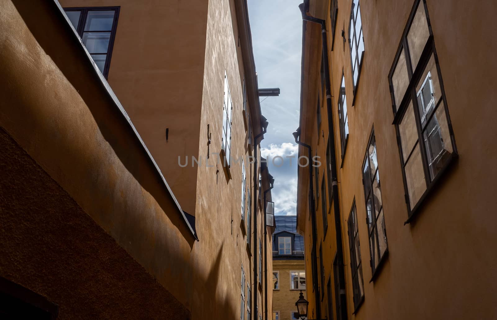 The narrow street of an old European city with yellow houses.