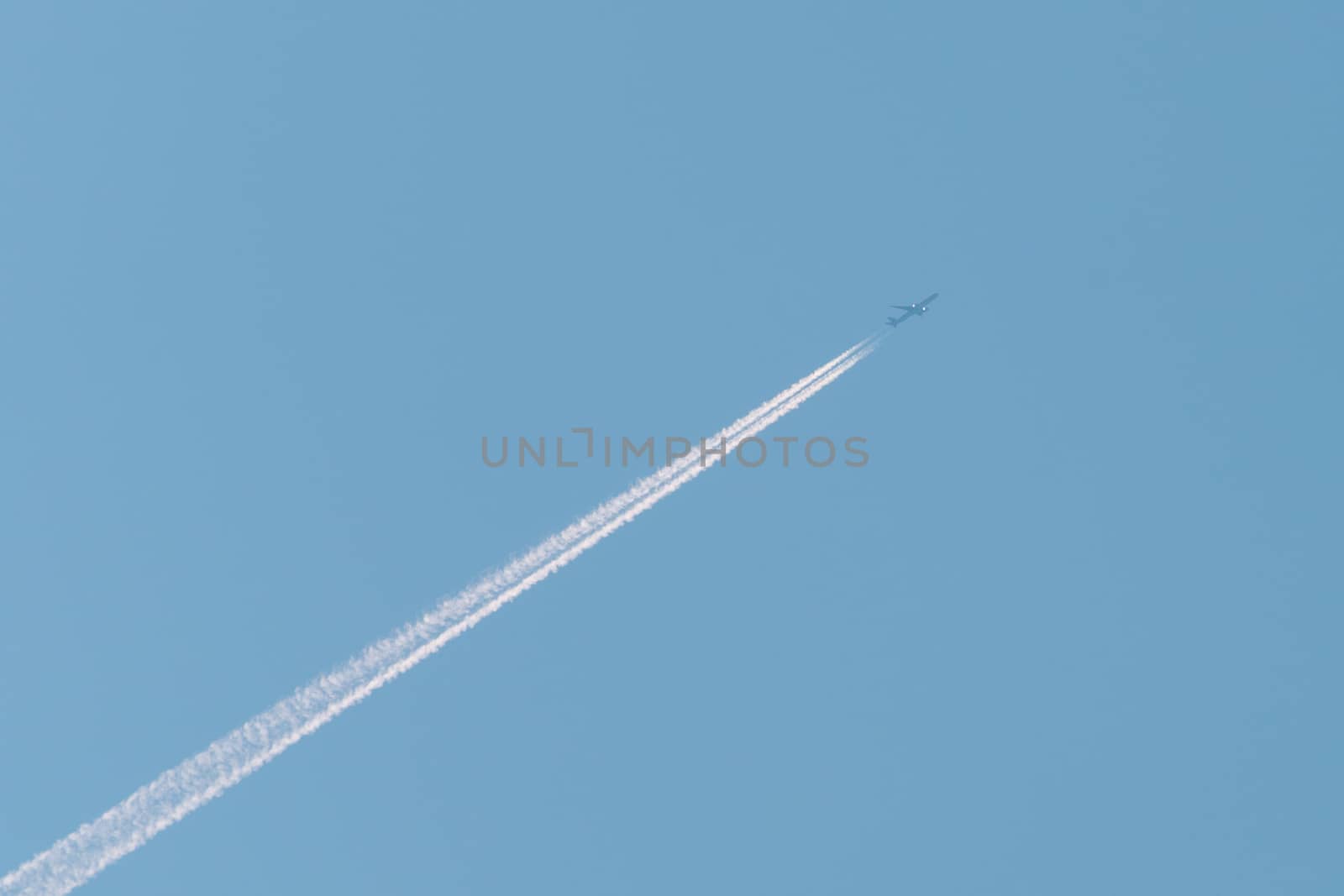 Jet passenger plane with reversing trail on a background of blue sky
