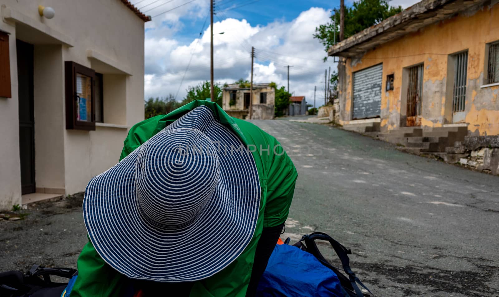 A girl in a wide-brimmed striped hat in a small village