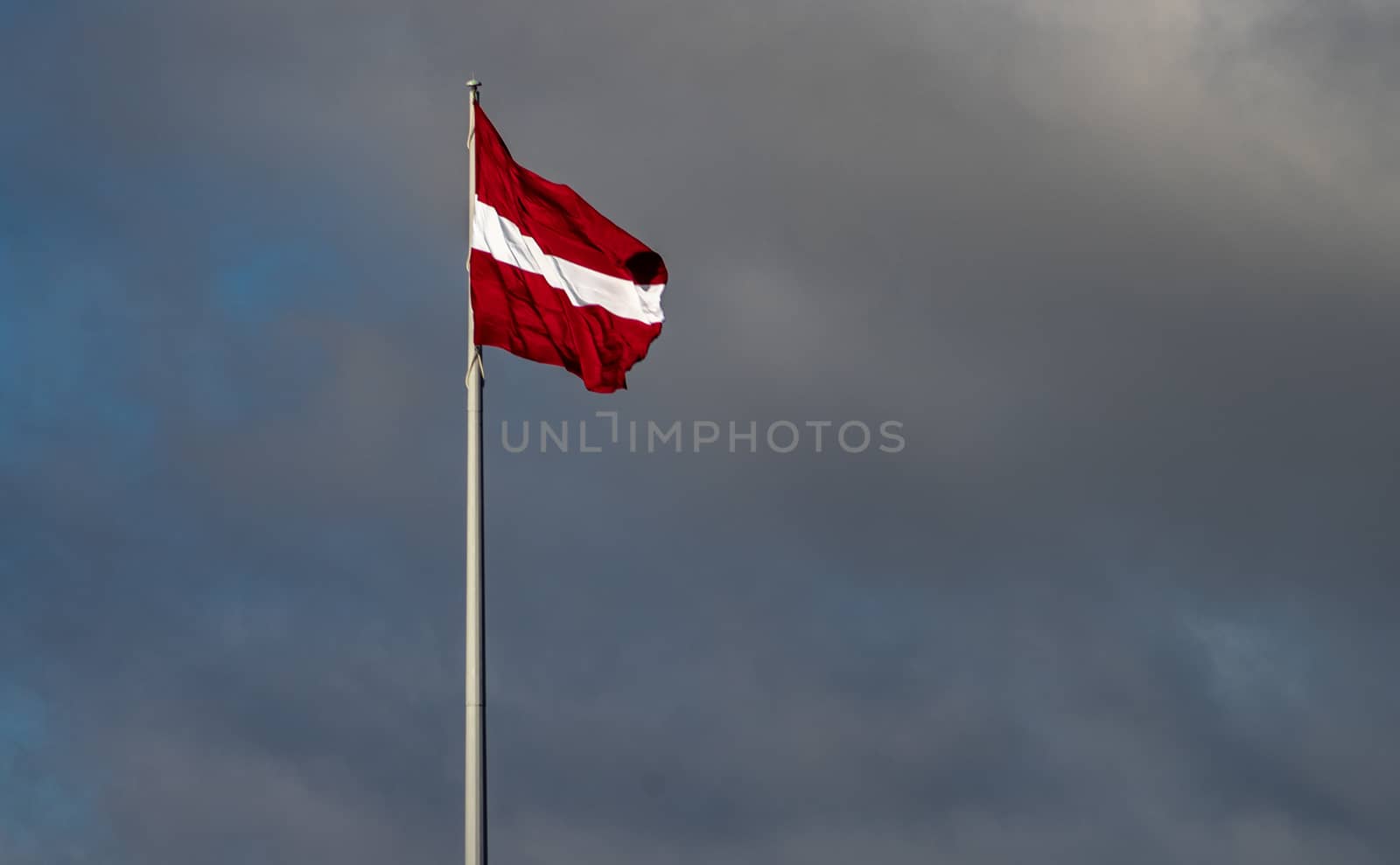 Bordeaux white flag of Latvia against a cloudy sky